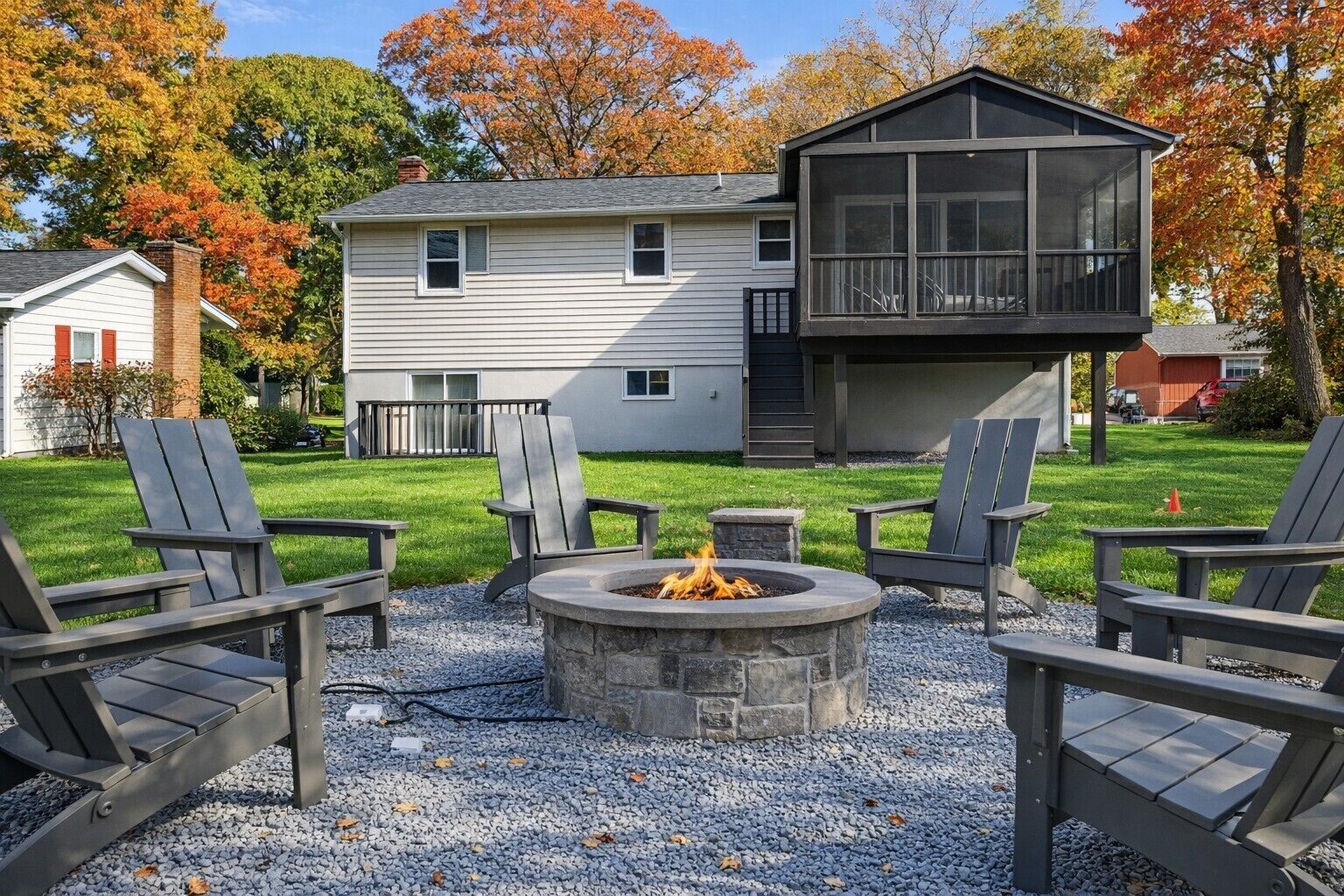 Un patio trasero con una chimenea, mobiliario exterior y una casa de dos pisos.