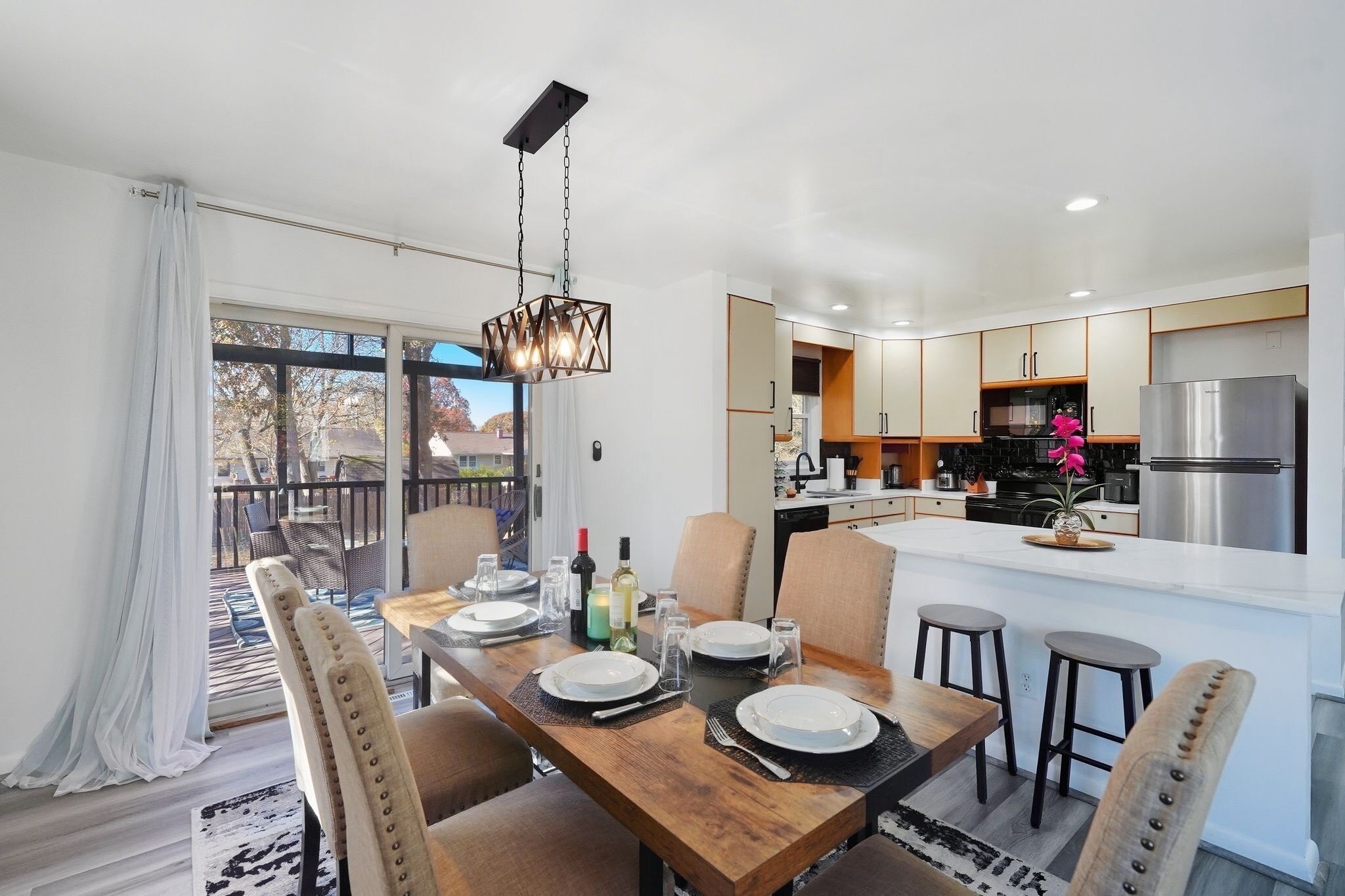 Une cuisine moderne dotée d’un îlot central, d’un coin repas avec des chaises et d’une vue sur l’extérieur.