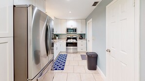 A modern kitchen with stainless steel appliances, white cabinets, and a blue patterned rug. - Bright Beachy 3BR Melbourne House—Dog‑Friendly with Screened Patio + Prime Location☀️🐕 (Melbourne)