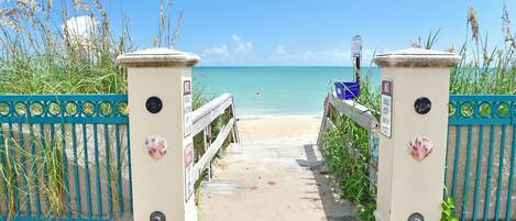 A beach entrance with a gate, pathway, and ocean view.