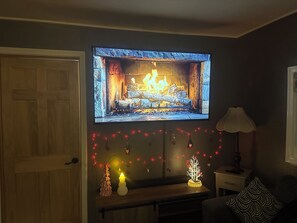 A room with a fireplace, a television mounted above it, and Christmas decorations. - The Grey Goose Hide Away, pet and family friendly with a small foot print. (Anchorage)