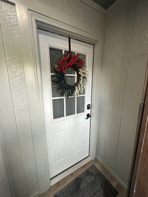A white door with a wreath, a window, and a doormat. - The Grey Goose Hide Away, pet and family friendly with a small foot print. (Anchorage)