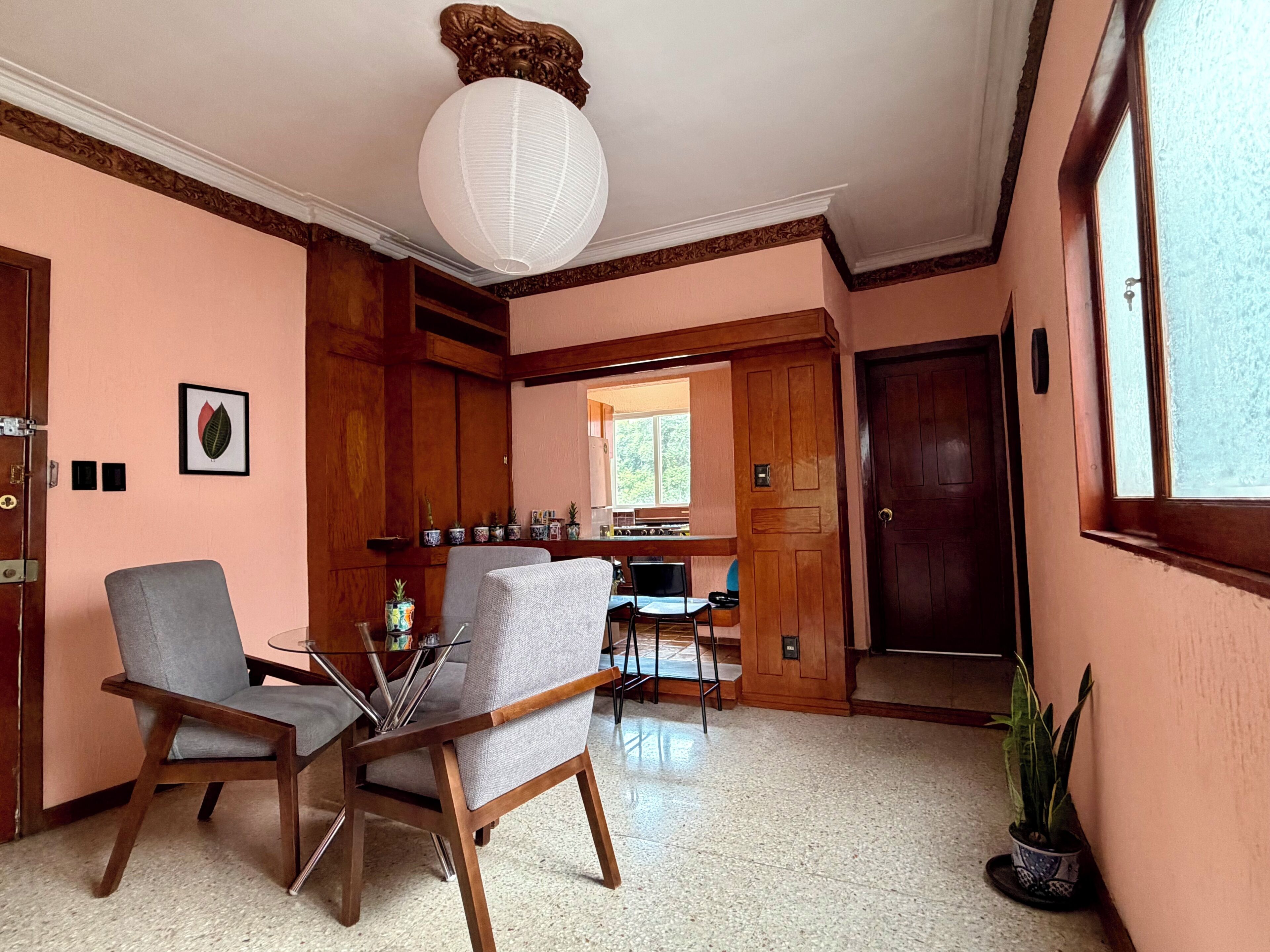 Une pièce comprenant deux chaises, une table, un luminaire au plafond, une porte et une fenêtre.