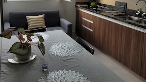 A modern kitchen with wooden cabinets, a dining table with a decorative table runner, and a view of the city through a large window. - Mirador del Cielo  (Santa Cruz)