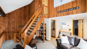 A wooden interior with a staircase, a leather sofa, and a sign reading 'EXPERTS ONLY'. - 1 Min to Cranmore - Sleeps 12 - 4 levels - Arcade Bunk Room- 3 Min to Downtown (North Conway)