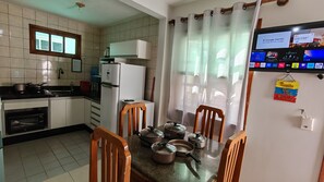 A kitchen with a refrigerator, stove, and dining table with chairs. - Entire apartment on Taperapuan beach - 300 meters from the beach.  (Porto Seguro)