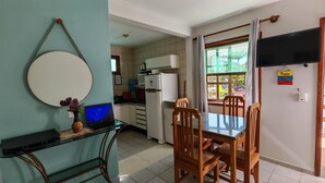 Een keuken met een koelkast, magnetron en een eettafel met stoelen.