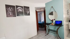 Un couloir avec un bureau, un ordinateur portable et un miroir. Trois tableaux encadrés sont accrochés au mur.