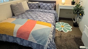 Ein Schlafzimmer mit einem Bett, einem Nachttisch, einer Lampe, einem Blumentopf und einem Fenster mit Blick.