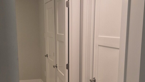 A hallway with wooden flooring and white doors. - Cozy Private One-Bedroom Suite With Separate Entrance—Dining set & kitchen (Dieppe)