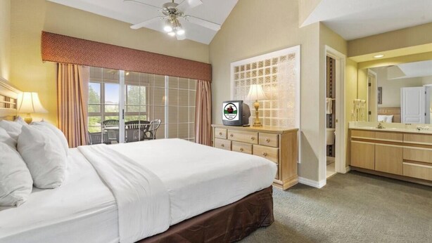 Una camera d'albergo con un letto, una televisione, una scrivania, una sedia e una finestra vista.