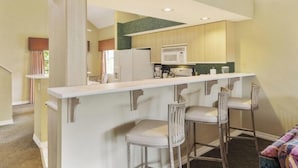 Una cucina moderna con isola centrale, sgabelli da bar e forno a microonde.