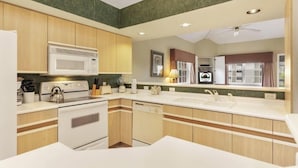 Una cucina moderna con mobili in legno, forno a microonde, piano cottura e lavastoviglie.