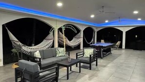 Un espacio interior amplio con mesa de billar, asientos y hamacas.