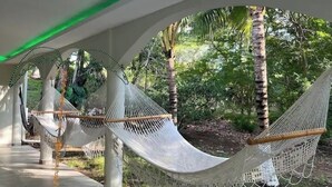 Un espacio al aire libre techado con hamacas y un sendero.
