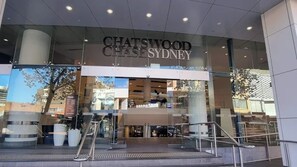 The entrance to Chatswood Chase Sydney with a modern glass facade, visible interior seating, and a clear view of the surrounding area. - Quiet and Cozy 2BR Home in Chatswood with Parking (Chatswood)