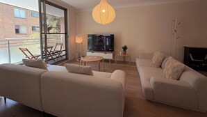Un soggiorno moderno con un divano, una televisione, una lampada e un balcone.