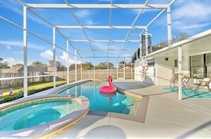An outdoor swimming pool with a pink flamingo float, surrounded by a covered area with a white metal frame. - Fantastic 4-bedroom house with pool in charming Kissimmee, 8minutes from Disney (Kissimmee)