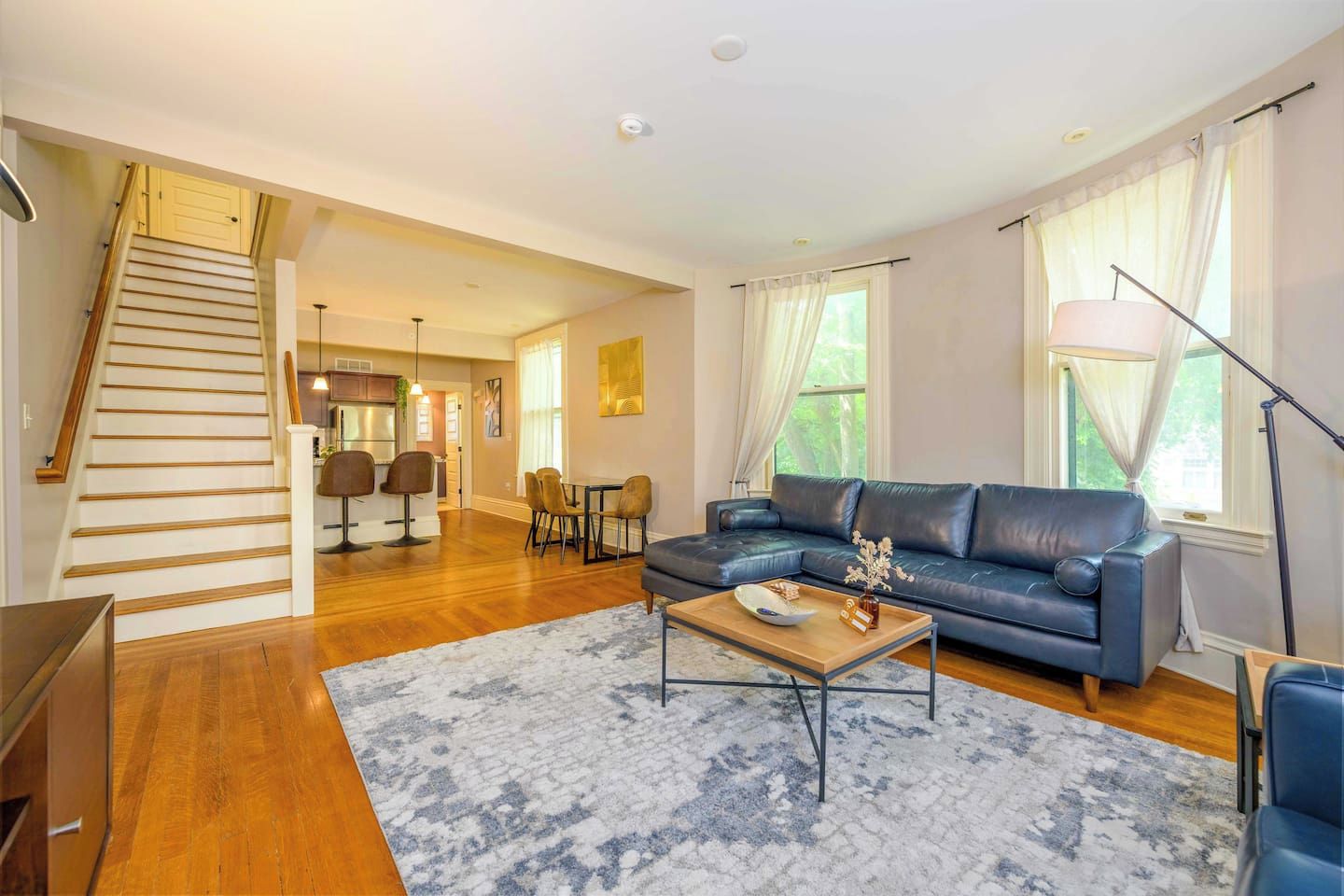 A spacious living room with a staircase, a dining area, and a sofa.