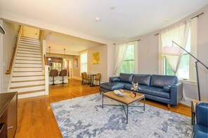 Un salon spacieux avec un escalier, un coin repas et un canapé.