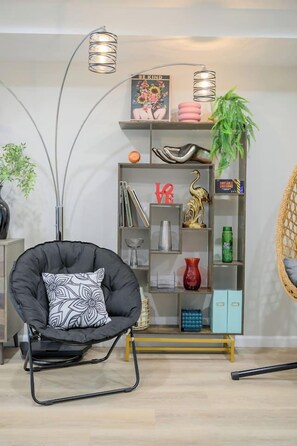 Ein modernes Wohnzimmer mit einem schwarzen Sitzsack, einer hohen Bücherwand und einem Hängesessel.