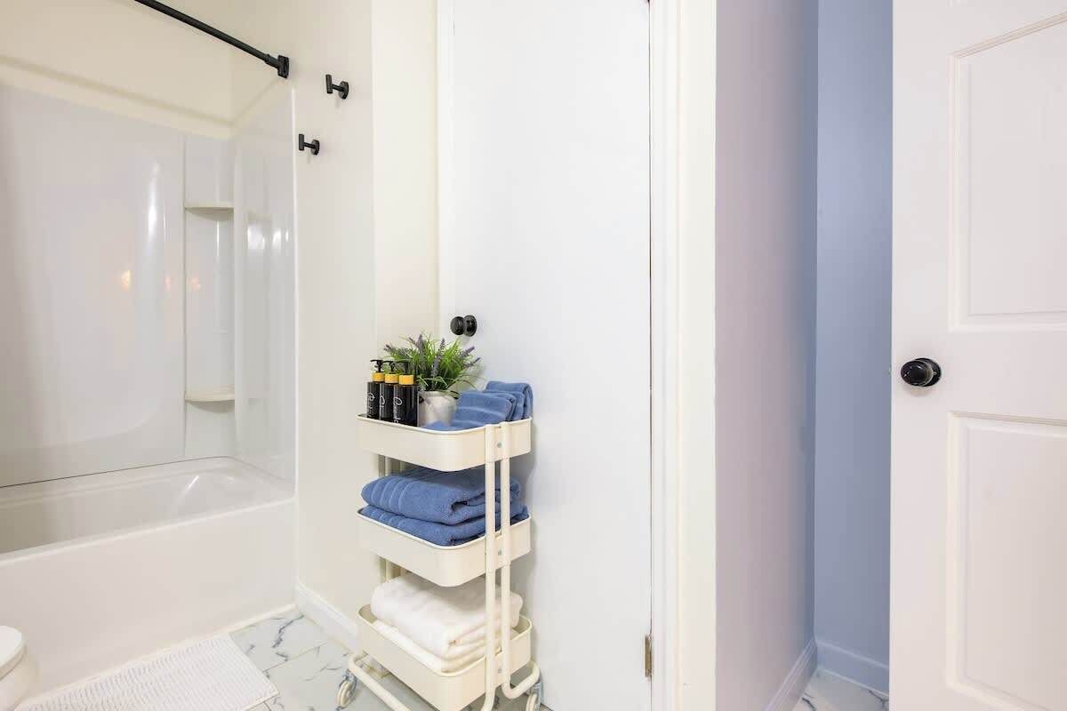 Une salle de bain avec une douche à parois de verre, un porte-serviettes blanc avec des serviettes et une plante en pot.