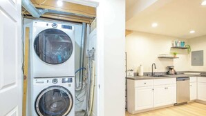 A laundry room with stacked washers and dryers, a kitchen with white cabinets, and a countertop with various items.