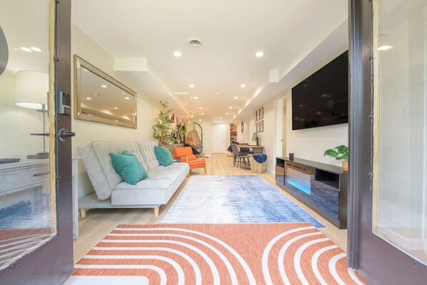 A modern living room with a sofa, a dining area, and a TV.