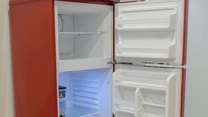 A compact red refrigerator with two door compartments, a freezer section, and a small shelf area.