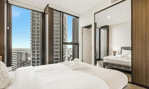 Camera d'albergo moderna con un letto grande, un letto più piccolo e vista su edifici alti.