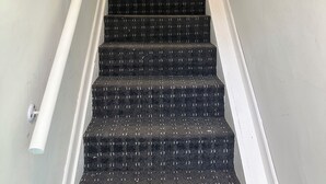 A staircase with black carpeted steps and white handrails. - Two bed flat in Manchester—Walk to Uni & Hospitals (Manchester)
