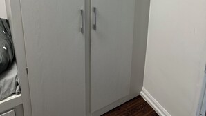 A closed wardrobe with two handles, a white wall, and a light switch. - Two bed flat in Manchester—Walk to Uni & Hospitals (Manchester)