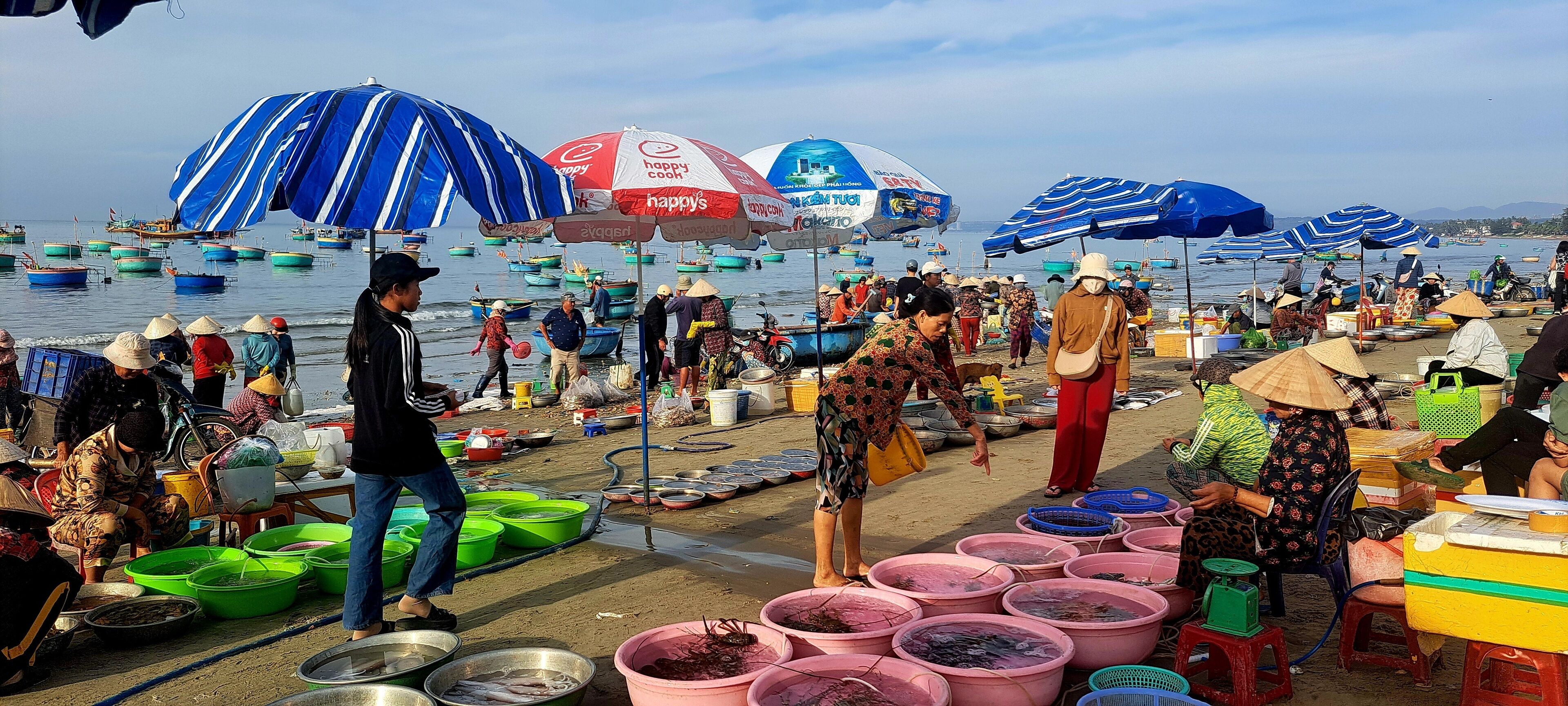 Une scène animée de marché, avec des vendeurs et des bateaux sur l’eau.
