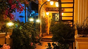 A nighttime outdoor area with hanging lanterns, potted plants, and a tiled pathway. - PHO Homestay Fishing Village  (Mui Ne)