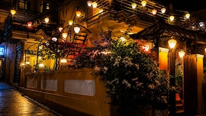 A night scene of a building with multiple floors, outdoor lighting, and a variety of plants. - PHO Homestay Fishing Village  (Mui Ne)