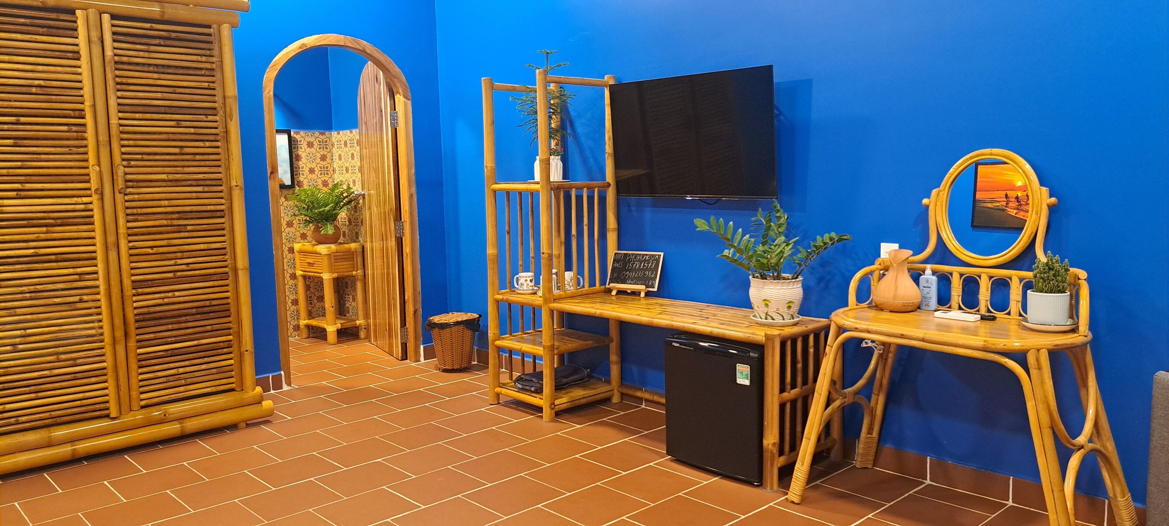 A room with a blue wall, a television mounted above a wooden table, and a mirror on the wall.
