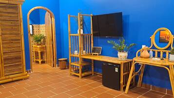 A room with a blue wall, a television mounted above a wooden table, and a mirror on the wall.