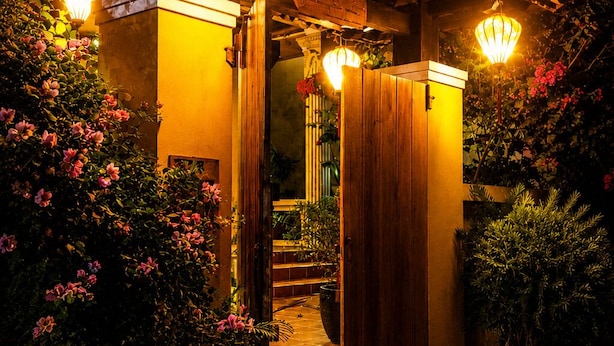 A building with a wooden facade, a staircase leading to an entrance, and several potted plants. - PHO Homestay Fishing Village  (Mui Ne)