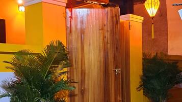 Une entrée d’immeuble avec une porte en bois, des plantes en pot et des lanternes suspendues.