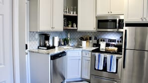 A compact kitchen with white cabinets, a built-in microwave, a stainless steel refrigerator, and a dishwasher. - Modern Hideaway: Steps from Sights & City Vibes (Little Rock)