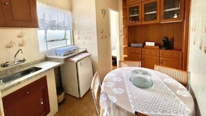 A compact kitchen with a sink, a small refrigerator, and wooden cabinets. - Cozy apartment in the Imperial Condominium (Lambari)