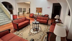 A spacious lobby with a grand staircase, red upholstered seating, and a large painting on the wall. - Cozy apartment in the Imperial Condominium (Lambari)