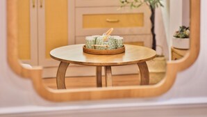 Una mesa redonda de madera con una bandeja de objetos decorativos en una habitación con paredes de tonos claros y armarios de madera.