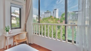 Una habitación con un ventanal grande, un escritorio con silla y un equipo de aire acondicionado.