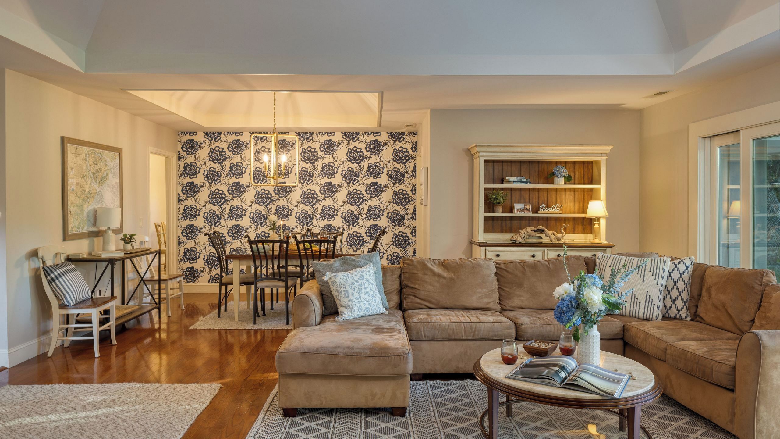 A living room with a sofa, coffee table, and a dining area with chairs and a table.
