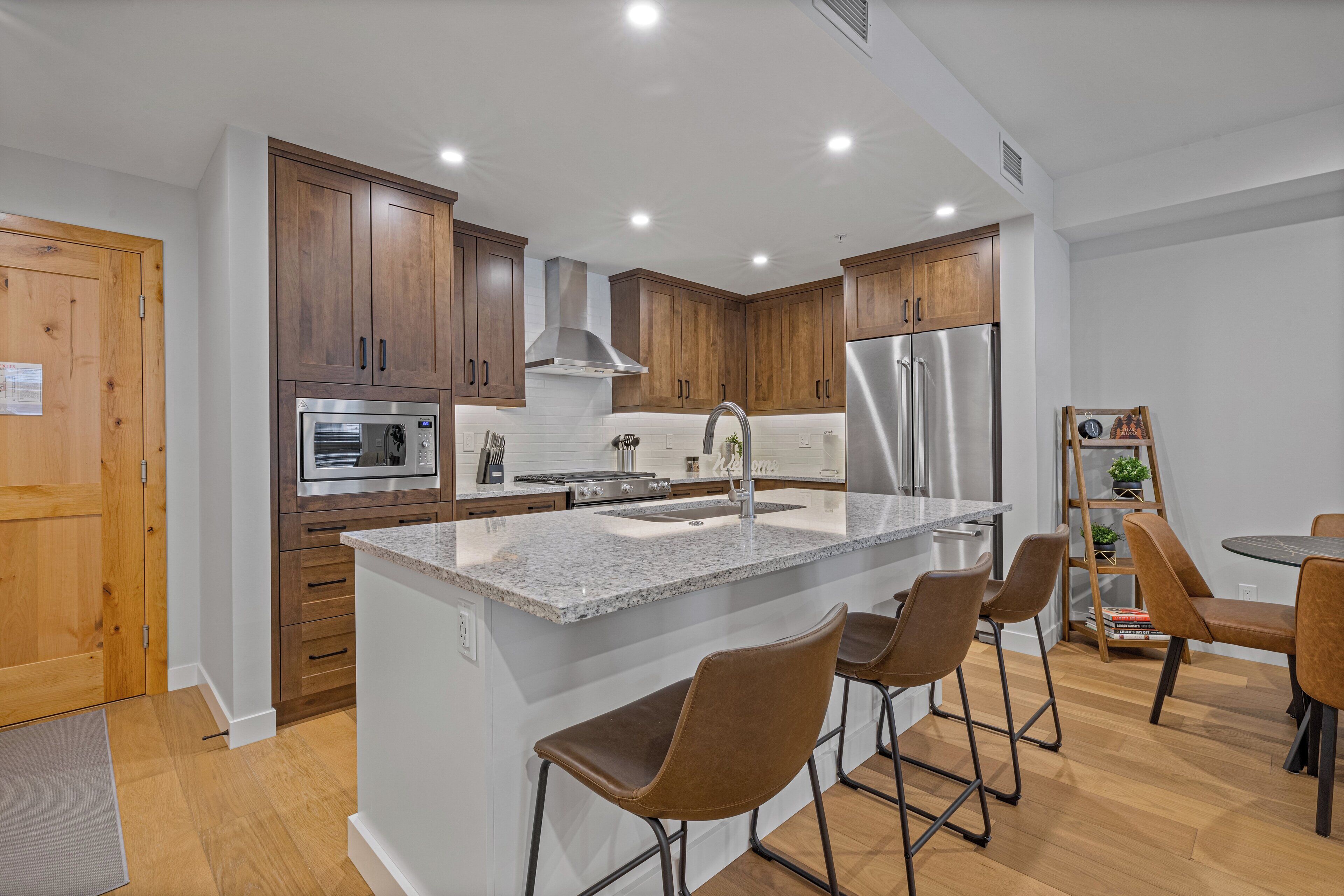 A modern kitchen with wooden cabinets, stainless steel appliances, and a central island with bar stools.