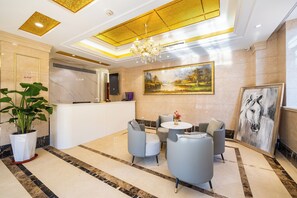 A lobby with a reception desk, seating area, and artwork on the walls. - world hotel qing dao zhan qiao (Qingdao)