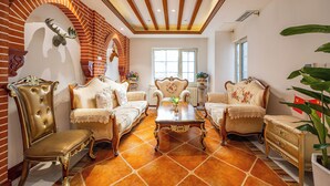 Un salon spacieux avec un mur en briques, une grande fenêtre et un plafond orné de poutres en bois.