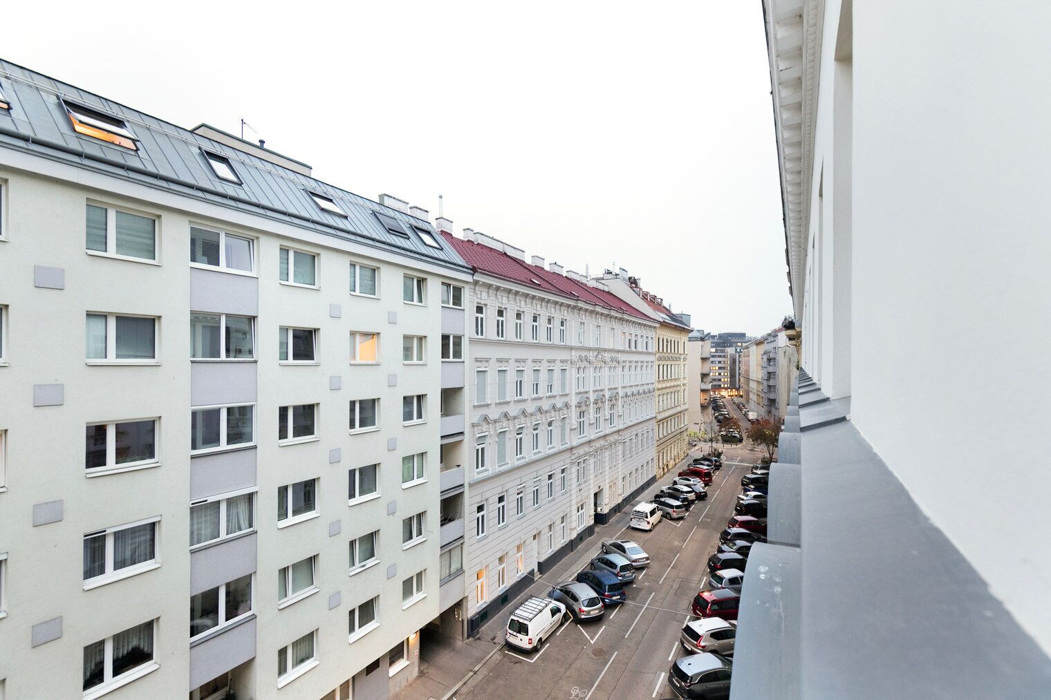 Une rangée d’immeubles résidentiels à plusieurs étages, avec un parking situé devant.