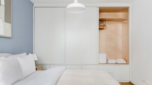 Quarto com cama, guarda-roupa e luminária pendente.